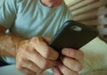 Crop face portrait with close up hands holding mobile phone of young man at home bedroom using internet social media app on smartp Royalty Free Stock Photo