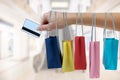 Crop female hand holding colorful paper bags on background of shopping center. black Friday