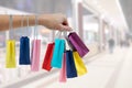 Crop female hand holding colorful paper bags on background of shopping center. black Friday