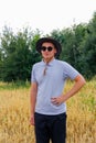 Crop field. Portrait of farmer standing in gold wheat field with blue sky in background. Young man wearing sunglasses Royalty Free Stock Photo