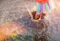 Crop girl playing in muddy puddle