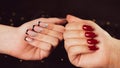 Crop girl& x27;s hand and woman& x27;s hand with different manicure. Unrecognizable females showing nail polish on black