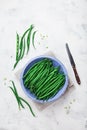 Crop of green or string beans in vintage bowl and knife on white stone background top view. Organic and diet food. Royalty Free Stock Photo