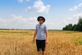 Crop and harvest. Portrait of farmer standing in gold wheat field with blue sky in background. Young man wearing Royalty Free Stock Photo