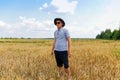 Crop and harvest. Portrait of farmer standing in gold wheat field with blue sky in background. Young man wearing Royalty Free Stock Photo