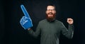 Crop panorama photo of a bearded man wearing a blue fan foam glove. Royalty Free Stock Photo