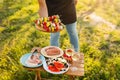 Crop person holding tray with raw vegetable kebabs over table with wineglasses
