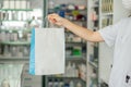 Crop pharmacist giving paper bag with medications to client Royalty Free Stock Photo