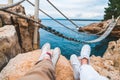 crop picture couple legs at cliff suspension bridge on background