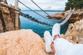 crop picture woman legs at cliff suspension bridge on background