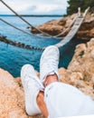 crop picture woman legs at cliff suspension bridge on background