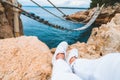 crop picture woman legs at cliff suspension bridge on background