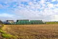 Crop plots after harvest with hay bales wrapped in green plastic sheets stacked in background Royalty Free Stock Photo