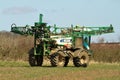 Crop sprayer parked and folding arms away in field