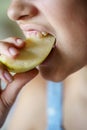 Crop teenage girl biting fresh juicy apple slice at home Royalty Free Stock Photo