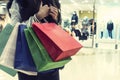 Crop unrecognizable girl clasping many shopping bags on mall background. Lady making many purchases in store. Concept of female