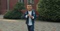 Crop view of happy little boy running and looking to camera. Child in school uniform with backpack smiling on his way to