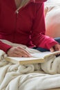 Crop view of young adult woman is relaxing on comfortable sofa with book