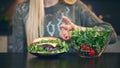 Crop view of Young lady preferring hamburger to salad.