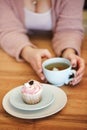 Crop woman with cupcake and cup of tea in cafe Royalty Free Stock Photo