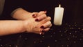 Crop woman praying with clasped hands. Crop unrecognizable religious female praying with folded hands at dark table with