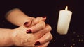 Crop woman praying with clasped hands. Crop unrecognizable religious female praying with folded hands at dark table with