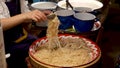 Crop woman putting noodles in bag. Unrecognizable female seller putting traditional Thai noodles in plastic bag while working in