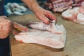 Crop worker cutting raw meat in butchery shop