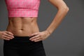 cropped close up body of fit woman wearing shorts and sport top showing slim beautiful stomach and abs in diet fitness