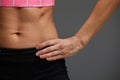 cropped close up body of fit woman wearing shorts and sport top showing slim beautiful stomach and abs in diet fitness