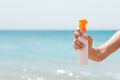 Croped image of woman`s hand holding sunblock spray at the beach