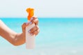 Croped image of woman`s hand holding sunblock spray at the beach