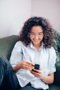 Croped photo of plasant woman surfing the Net on phone on sofa