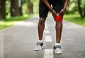 Cropped of black sportsman touching his inflamed knee
