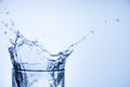 Cropped close up image of glass top full of tasty fresh clear drinkable tap water with high splash isolated over light blue white Royalty Free Stock Photo