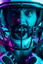 Cropped close-up image of professional american footblall player in protective helmet isolated over dark purple