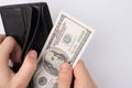 Cropped close up photo of male hands taking last 100 dollars from the leather black wallet  over grey background with Royalty Free Stock Photo