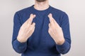 Cropped close-up photo portrait of unsure unconfident guy making crossed finger isolated grey background