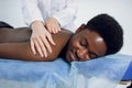 female doctor making professional massage therapy for male Afro-American patient Royalty Free Stock Photo