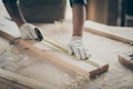 Cropped close-up view of his he nice hands swearing gloves skilled experienced guy expert measuring plank board building Royalty Free Stock Photo