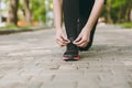 Cropped close up of woman hands tying shoelaces on black and pink sneakers on jogging or training on path outdoors Royalty Free Stock Photo