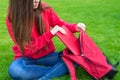 Cropped closeup photo of beautiful charming teen girl packing stuff into opened schoolbag sitting on green grass lawn inside the Royalty Free Stock Photo