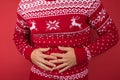 Cropped closeup photo of man in red and white christmas sweater holding his hurting stomach on isolated red background Royalty Free Stock Photo