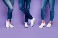 Cropped closeup photo of three people`s legs wearing denim dark blue jeans trousers pants standing on the floor isolated