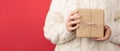 Cropped closeup photo of young woman in white knitted sweater holding craft paper gift box with twine bow on isolated red Royalty Free Stock Photo