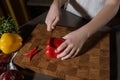 Cropped closeup portrait of kid's hands cutting red bell pepper