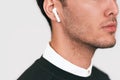 Cropped closeup portrait of serious young handsome man posing with wireless earphones on white studio background. Royalty Free Stock Photo