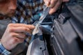 Cropped closeup view man working in garage applying protective film on headlamp Royalty Free Stock Photo