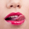 Cropped closeup of a woman wearing lipstick and licking her lip