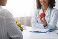 Cropped of dietician recommending female patient fresh apple